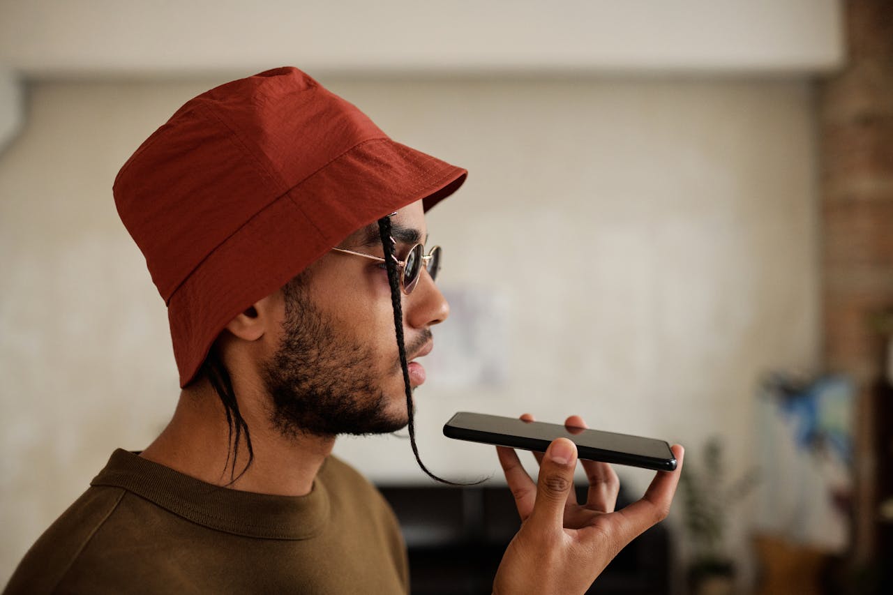 product-03 Profile view of a man in a red bucket hat talking on a smartphone indoors.